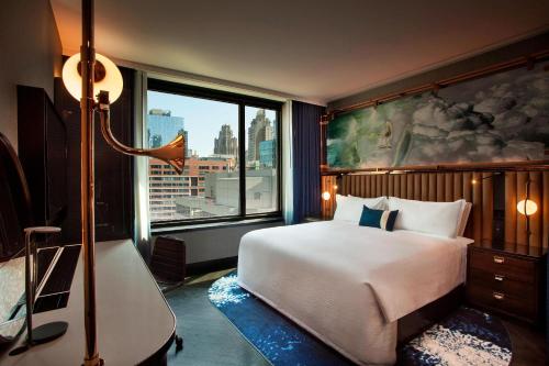 a bedroom with a bed and a large window at Hotel EMC2, Autograph Collection in Chicago