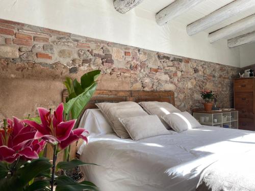 a bedroom with a white bed and a brick wall at L'ESTABLE DE CAN TABERNER in Bigues i Riells