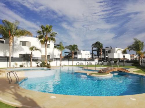 een groot zwembad met palmbomen en gebouwen bij Holiday Home in Residence KOMA in Torrevieja