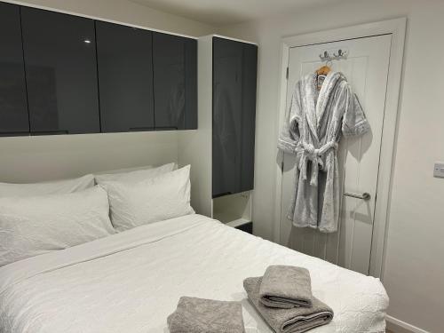 a bedroom with a bed and a robe hanging on a door at 1 bedroom guesthouse including parking on premises in Braintree