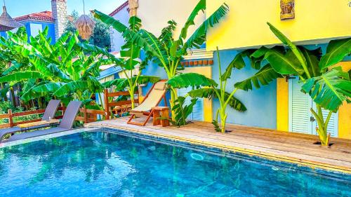 a swimming pool in front of a house with palm trees at Alaçatı Wellness Garden in Alacati