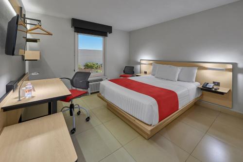 een hotelkamer met een bed, een bureau en een raam bij City Express by Marriott Cancun in Cancun