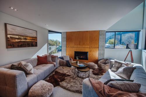 a living room with a couch and a fireplace at Award-Winning Modern Retreat with Hot Tub & Views in Queenstown