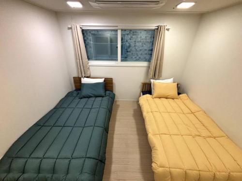 two beds sitting in a room with a window at Clean 2 SuperSingle Beds House in Seoul