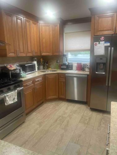 a kitchen with wooden cabinets and stainless steel appliances at Home away from home in Laurelton