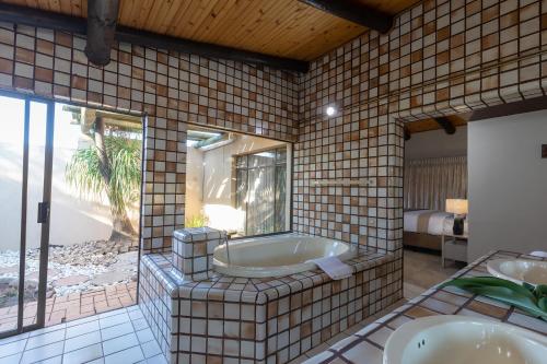 a bathroom with two sinks and a bath tub at The Pal Guest House in Gaborone