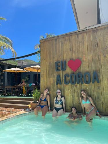 quatro mulheres na piscina de um resort em A Coroa Hostel & Suites em Arraial do Cabo