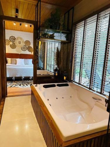 a large white bath tub in a room with windows at Vale dos Bugres Eco House- Cabana das Flores in Urubici