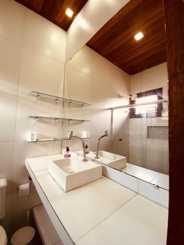 a white bathroom with two sinks and a toilet at Casa Vida Li in Ilha de Boipeba