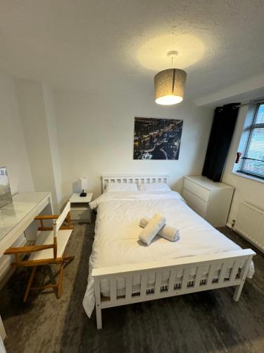 Biała sypialnia z białym łóżkiem i biurkiem w obiekcie West Midlands Contractors, Nurses and Families 