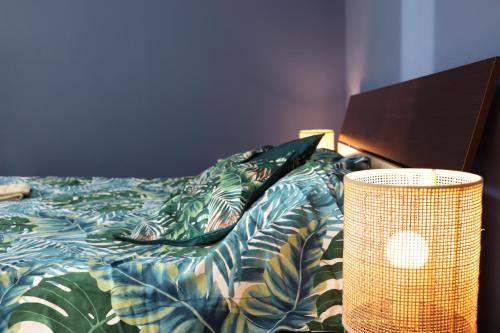 a bed with a comforter and a lamp next to it at Center Apartment Dunja in Subotica