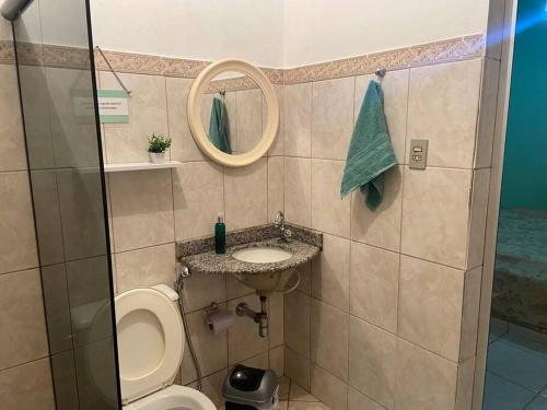 La salle de bains est pourvue de toilettes, d'un lavabo et d'un miroir. dans l'établissement Casa à beira lago de Furnas. (Pé na água), à Formiga