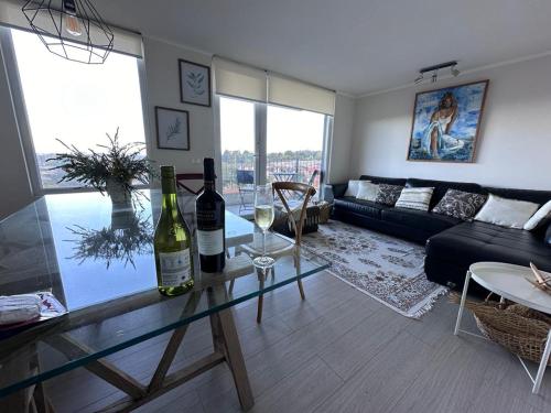 una sala de estar con 2 botellas de vino en una mesa de cristal en Hermoso depa, en Puerto Varas