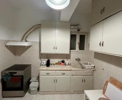 a kitchen with white cabinets and a sink at Spacious 2BDs Apt With Acropolis View In Center in Athens