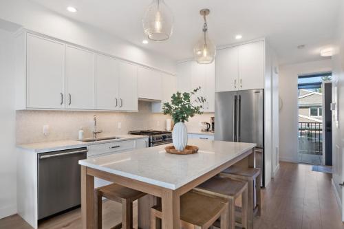 a kitchen with white cabinets and a table with a vase on it at Ocean's 7 at THE BEACH HOUSE in Campbell River