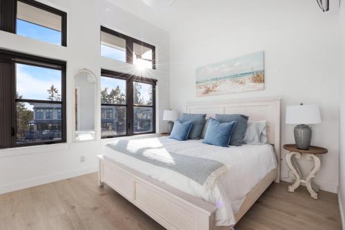 a white bedroom with a large bed with blue pillows at Ocean's 7 at THE BEACH HOUSE in Campbell River