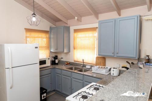 a kitchen with blue cabinets and a white refrigerator at Serendipity in The Villages in Christ Church