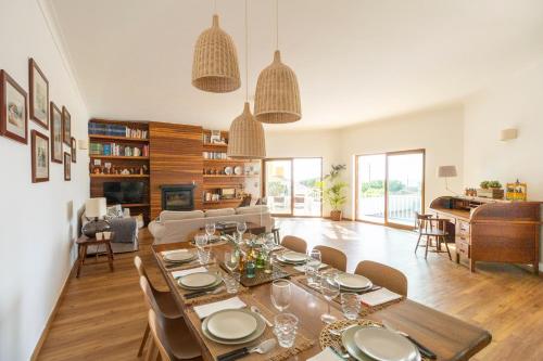 a dining room and living room with a table and chairs at Family beach house, sea view, pool, Colares near Sintra in Colares
