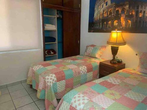 a bedroom with two twin beds and a lamp at Depa Los abuelos en Puerto Vallarta in Puerto Vallarta