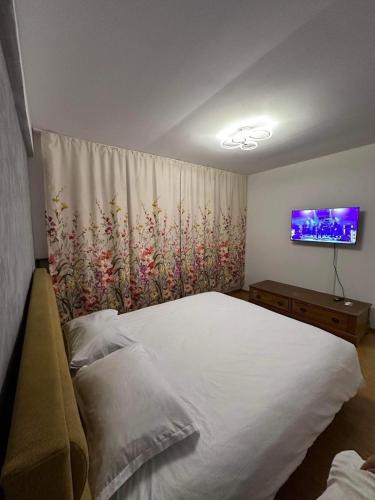 een slaapkamer met een groot wit bed en een televisie bij LukApartaments in Tulcea