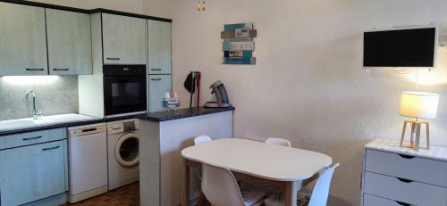 une cuisine avec une machine à laver, une table et un évier dans l'établissement Location appartement bord de mer Barcarès, au Barcarès