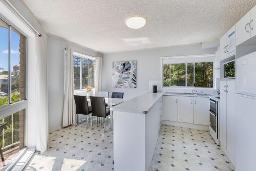 a kitchen with white cabinets and a table with chairs at Skyline Unit 12 in Gold Coast