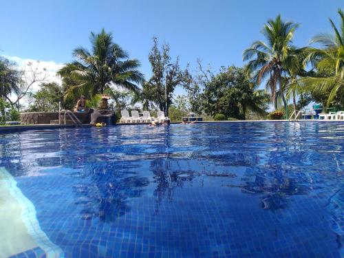 une grande piscine avec des palmiers en arrière-plan dans l'établissement Villa, KOCORU Casa de campo y playa, à Puntarenas