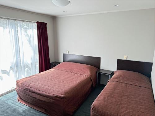 a bedroom with two beds and a window at Arena Lodge in Palmerston North