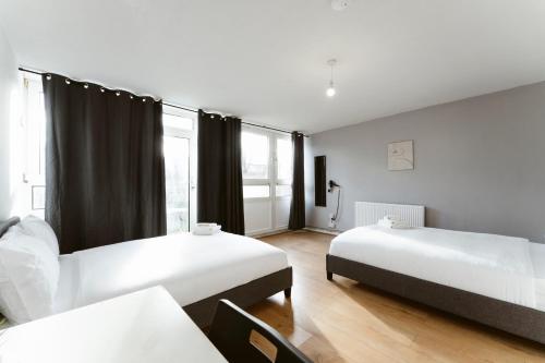 une chambre avec deux lits et une grande fenêtre dans l'établissement Langdon Park Room, à Londres