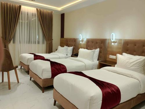 een hotelkamer met 3 bedden en een bureau bij Motel Abdelhamid in Ouled Moussa
