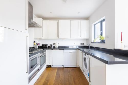 uma cozinha branca com armários brancos e piso em madeira em Luxury Penthouse In Central London em Londres
