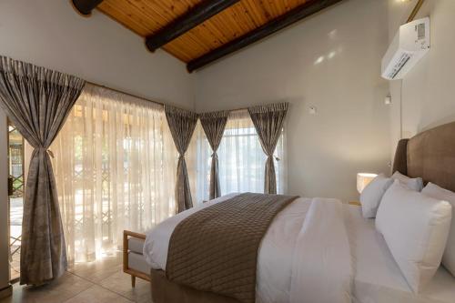 a bedroom with a bed and a window with curtains at The Pal Guest House in Gaborone