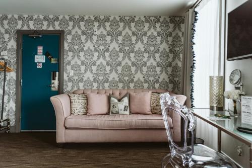 a pink couch in a living room with a blue door at The Grove Hotel in Kingsville