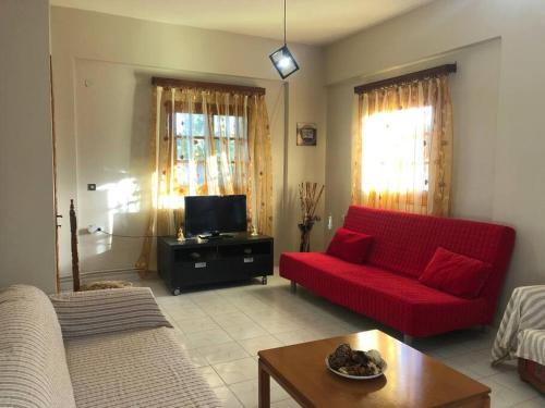 Earthly Paradise في Ambelókipoi: غرفة معيشة مع أريكة حمراء وتلفزيون