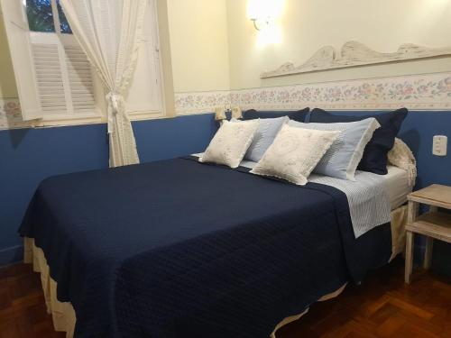 um quarto com uma cama azul e almofadas brancas em POUSADA NAO ME DEIXES em Paty do Alferes