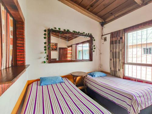 two beds in a room with a mirror at Joyas Del Sol Hotel in San Pedro La Laguna