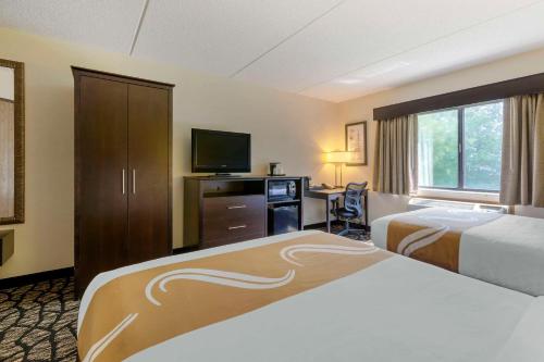 a hotel room with two beds and a television at Quality Inn in Oshkosh