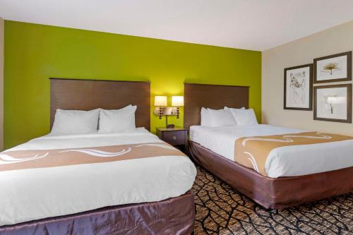 two beds in a hotel room with green walls at Quality Inn in Oshkosh