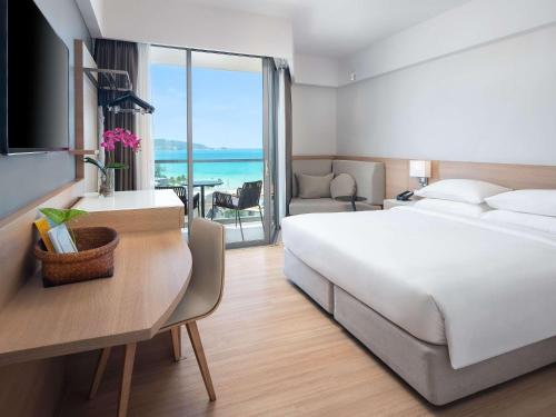 Habitación de hotel con cama y escritorio con vistas. en Andaman Beach Hotel Phuket - Handwritten Collection, en Patong Beach