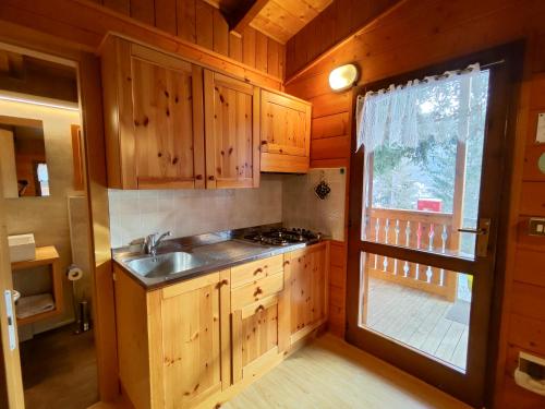 a kitchen with wooden cabinets and a sink and a window at Camping Val di Sole in Peio