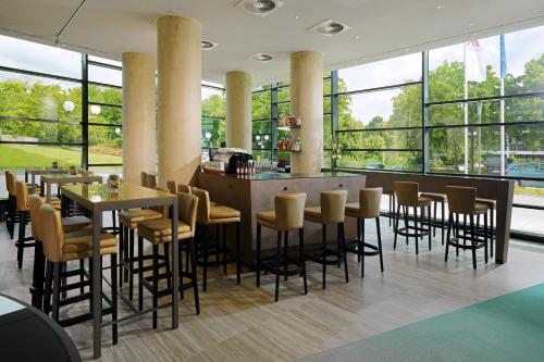 un restaurante con mesas, sillas y ventanas grandes en Bonn Marriott Hotel, en Bonn