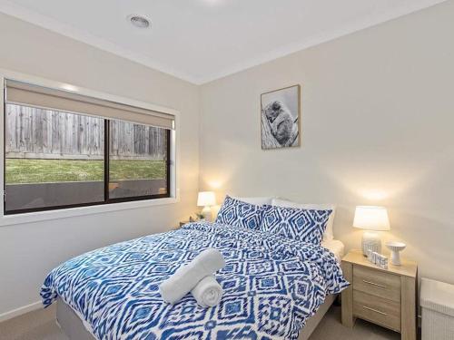 Un dormitorio con una cama azul y blanca y una ventana en 11a Railway Parade Wandin North, en Wandin North