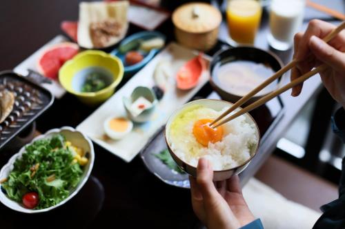 a person eating a bowl of rice with chopsticks at Beautiful Japanese Garden Kagetsu in Fuefuki