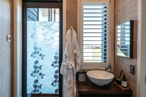 a bathroom with a sink and a shower with a tub at Tradewinds Waiheke in Church Bay 