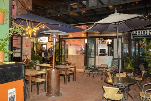 ein Restaurant mit Tischen, Stühlen und Sonnenschirmen in der Unterkunft Habitación privada – Super lugar in Bogotá
