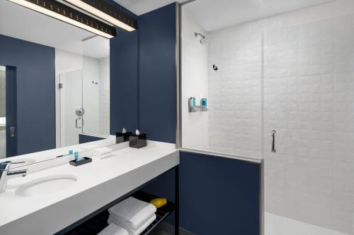 W łazience znajduje się umywalka oraz prysznic z lustrem. w obiekcie Aloft Delray Beach w mieście Delray Beach