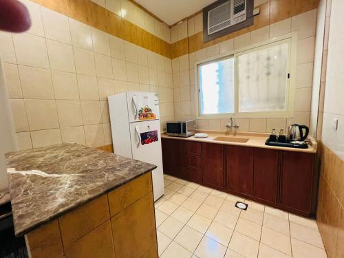 a kitchen with a white refrigerator and a sink at المهيدب للشقق المخدومة in Al Fuḑūl