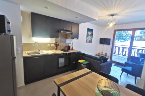 eine Küche und ein Wohnzimmer mit einem Tisch und einem Sofa in der Unterkunft Superbe appartement au pied des pistes in La Feclaz
