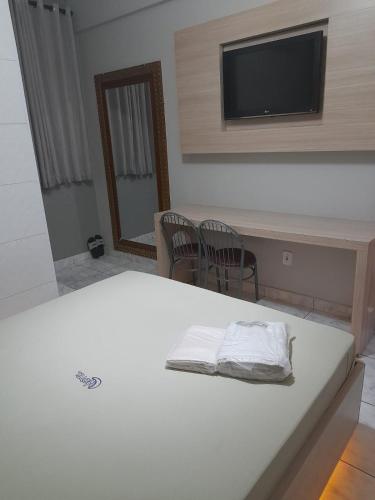 a white bed with two chairs and a tv on a wall at Motel Reality in Sao Paulo