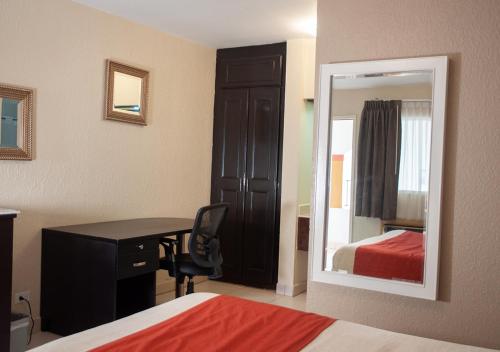 a bedroom with a desk and a mirror and a bed at Del Mar Inn Playas in Tijuana
